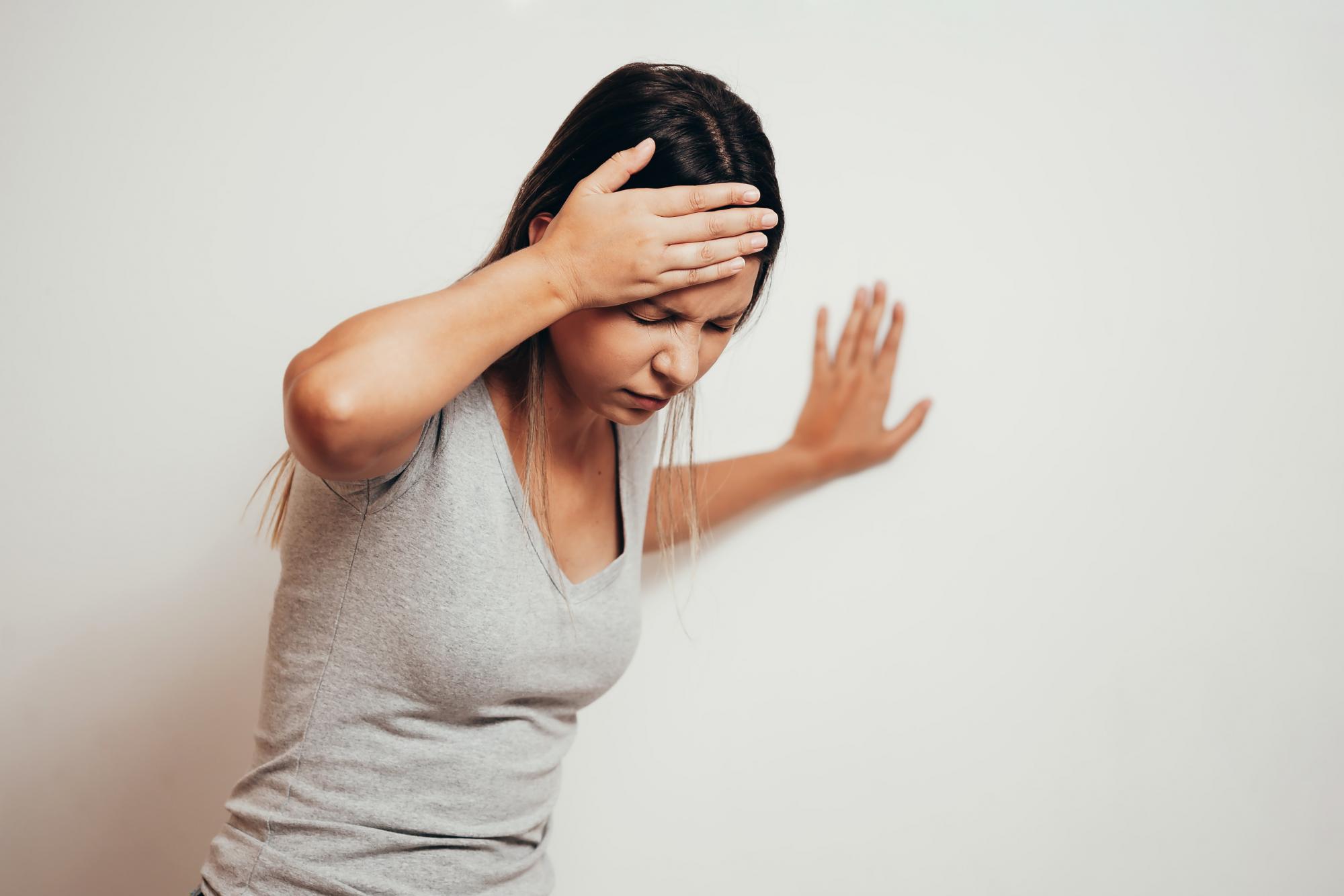 Woman holding her head due to dizziness when standing